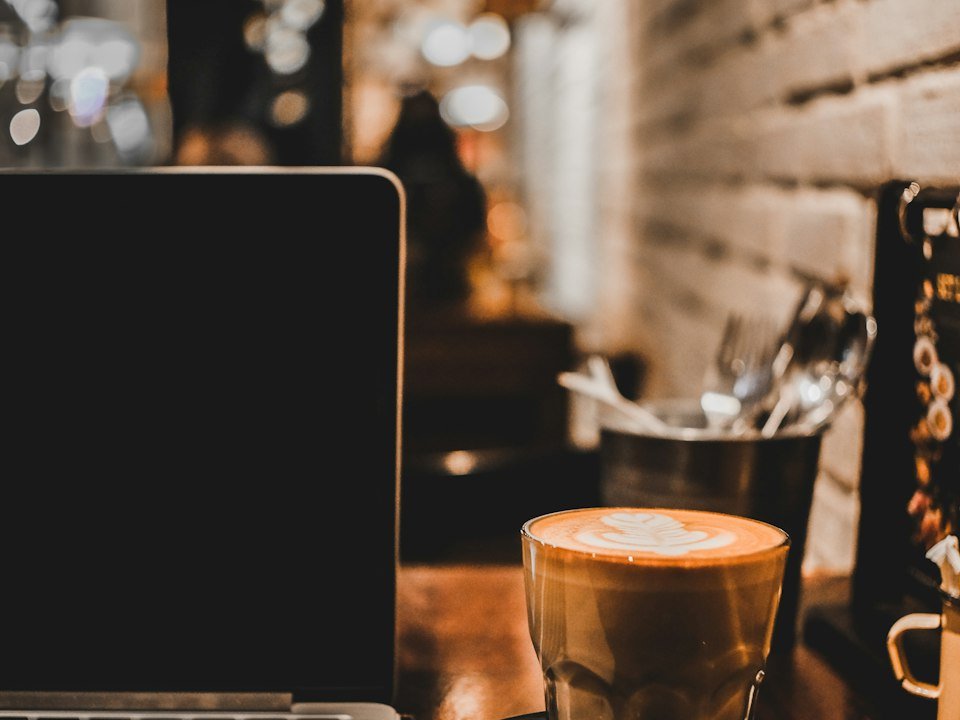 Clear glass coffee cup next to a laptop