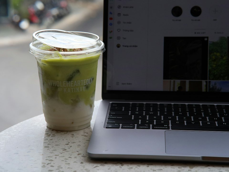 A cup of green tea beside a laptop